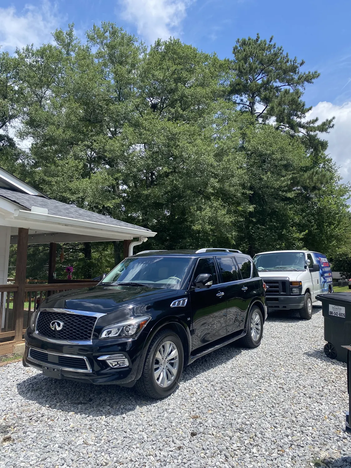 Black Infiniti QX80 SUV windshield replacement in a driveway