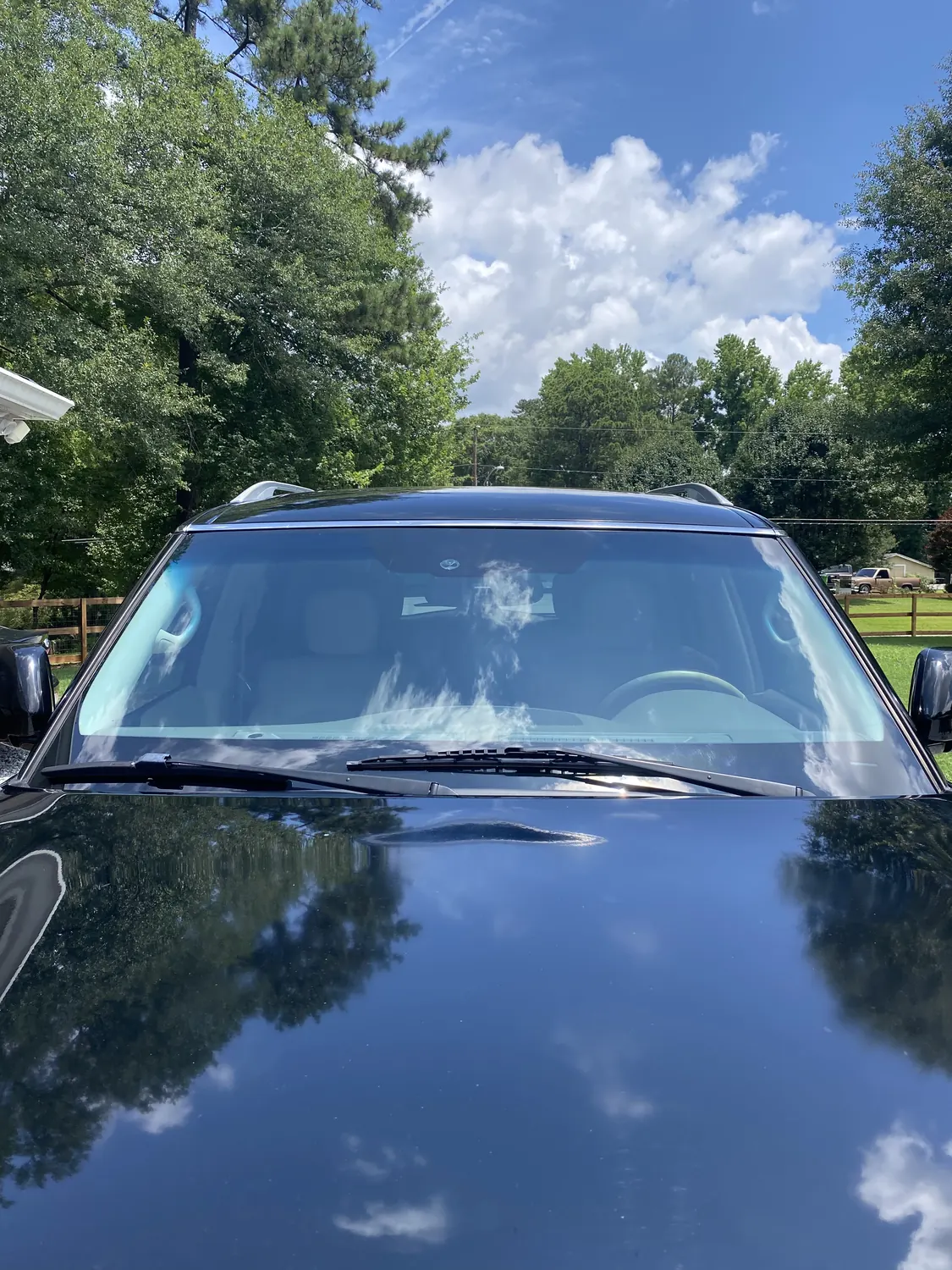 Dark sedan windshield with sky reflection after replacement